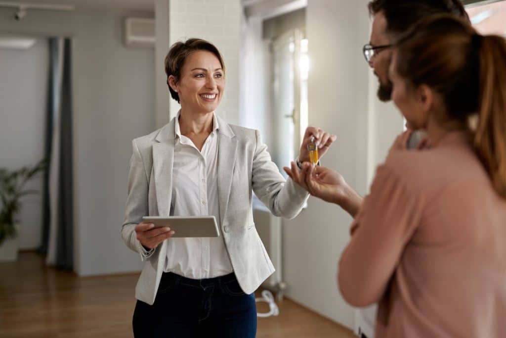 Happy real estate agent giving to a couple keys of their new home